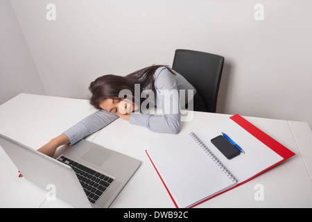 Épuisé businesswoman sleeping at office desk Banque D'Images