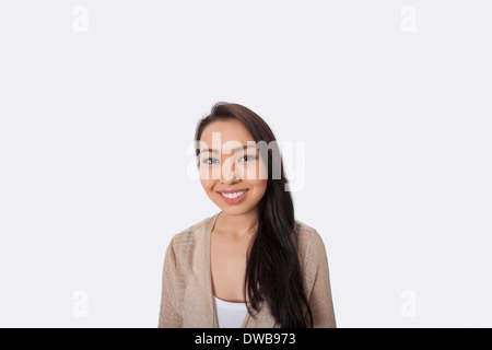 Portrait of happy young woman standing against gray background Banque D'Images