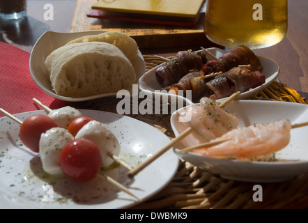 La mozzarella, tomates crevettes tapas, des dates avec du bacon et de la bière à Mallorca, Espagne. Banque D'Images