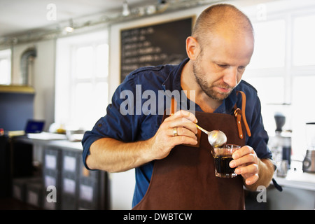 Café barista mâle en remuant le verre dans le café-bar Banque D'Images