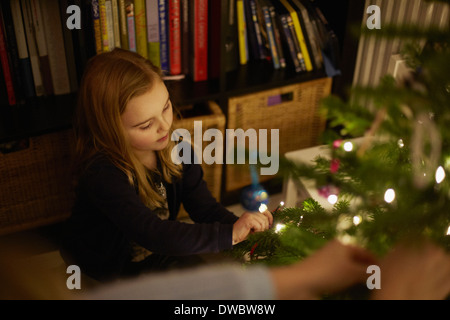 Young Girl decorating Christmas Tree with baubles Banque D'Images