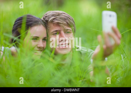 Jeune couple self-photographing on grass Banque D'Images