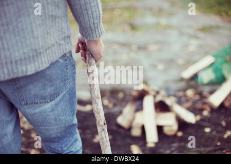 Vue arrière de l'abdomen man holding stick en camping Banque D'Images