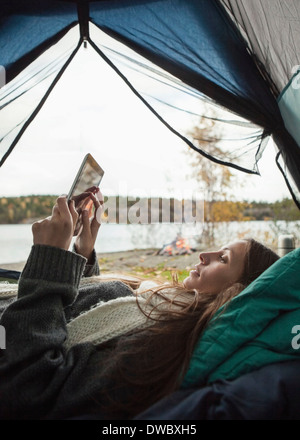 Side view of young woman using digital tablet in tent Banque D'Images