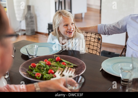 Happy girl en train de déjeuner avec la famille à table à manger Banque D'Images