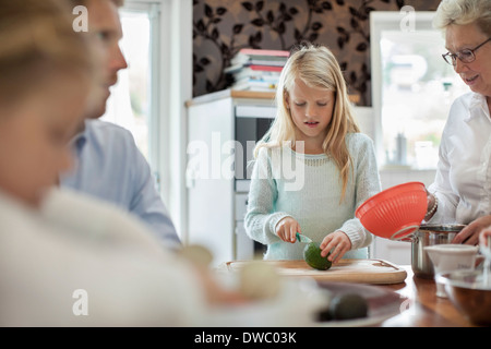 Girl couper des légumes pendant la cuisson en famille dans la cuisine Banque D'Images