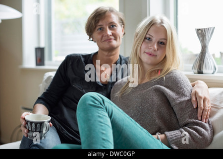 Portrait of mother and daughter sitting in living room Banque D'Images