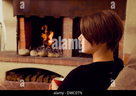 Jeune femme assise sur un canapé avec une tasse de café Banque D'Images