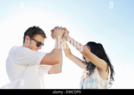 Young couple holding hands with arms raised Banque D'Images