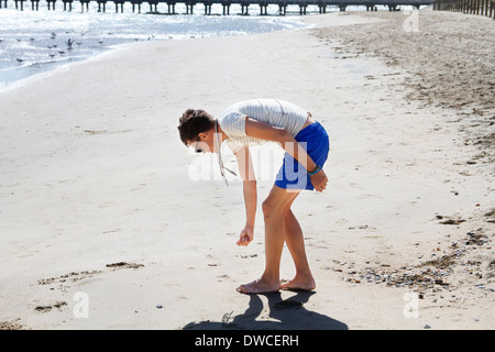 Jeune homme à la recherche de coquillages sur la plage, à Port Melbourne, Melbourne, Australie