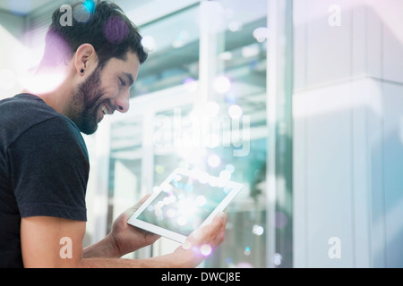 Mid adult man looking at digital tablet lumineux provenant de Banque D'Images