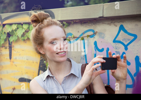 Young woman taking photograph sur smartphone Banque D'Images