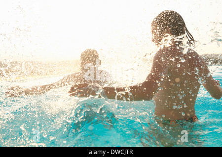 Couple, éclabousser autour de piscine extérieure Banque D'Images