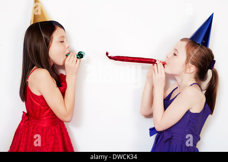Portrait de deux jeunes filles blowing party blowers Banque D'Images