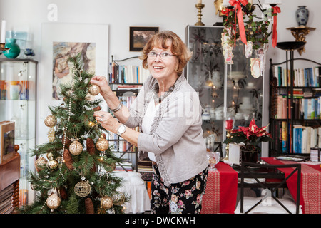 Senior adult woman decorating Christmas Tree Banque D'Images