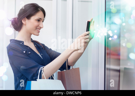 Young businesswoman looking at smartphone avec des lumières qui s'en Banque D'Images