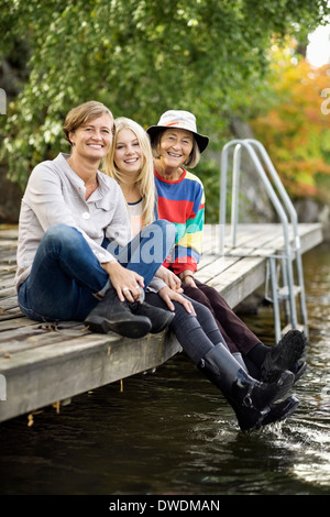 Portrait de trois femmes génération sitting on pier Banque D'Images