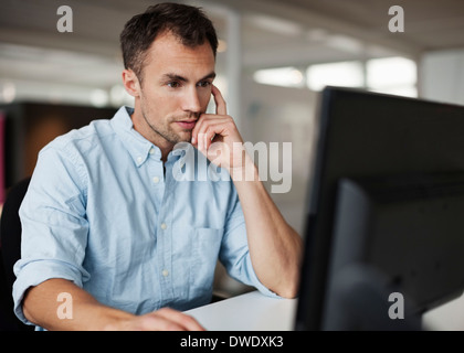 Businessman using desktop PC at desk in office Banque D'Images