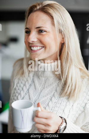 Smiling businesswoman holding coffee mug in office Banque D'Images