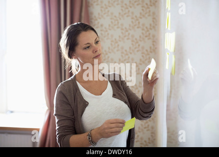 Businesswoman coller note notes sur tableau blanc Banque D'Images