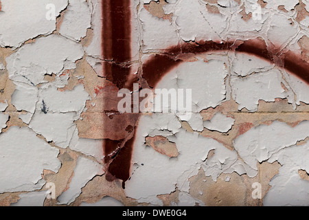 Un mur peint peeling avec graffiti rouge foncé. Banque D'Images