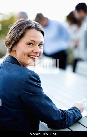 Portrait of happy businesswoman at patio avec des collègues en arrière-plan Banque D'Images