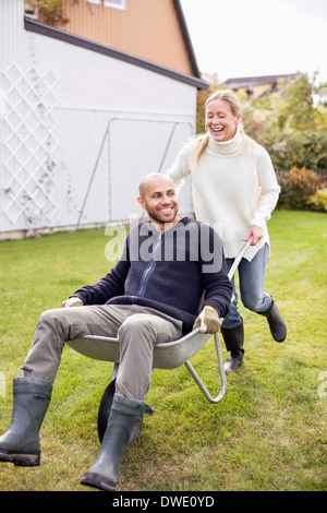 Happy woman man en brouette at yard Banque D'Images