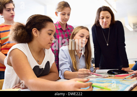 Avec l'enseignant les élèves qui étudient la carte at desk in classroom Banque D'Images