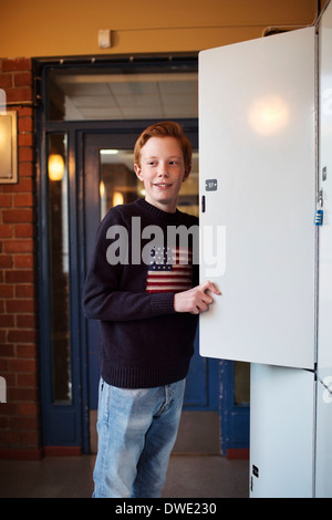 High school boy standing par locker Banque D'Images