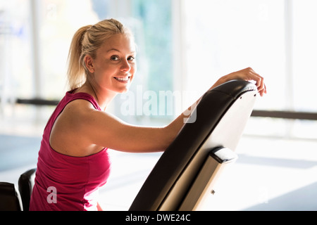 Portrait of smiling young woman sitting on chair at gym Banque D'Images