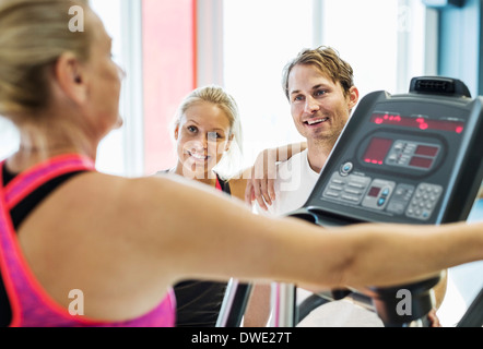 Les amis à la femme à l'exercice sur tapis roulant à la salle de sport Banque D'Images