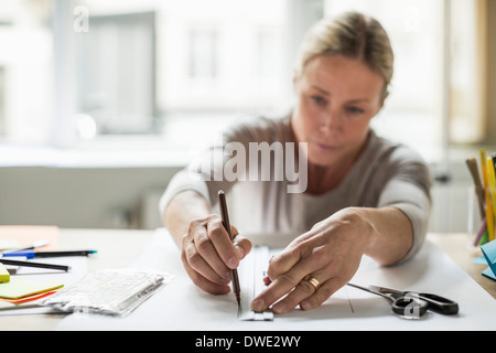 Businesswoman drawing ligne à l'aide de règle sur papier Banque D'Images