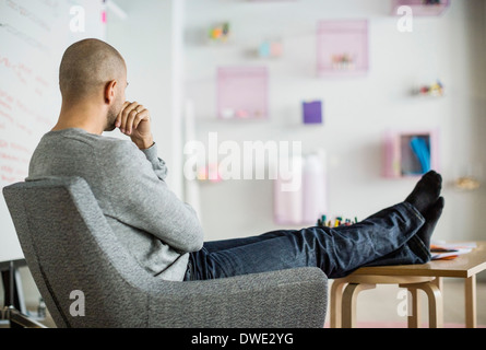 Thoughtful businessman sitting in creative office Banque D'Images