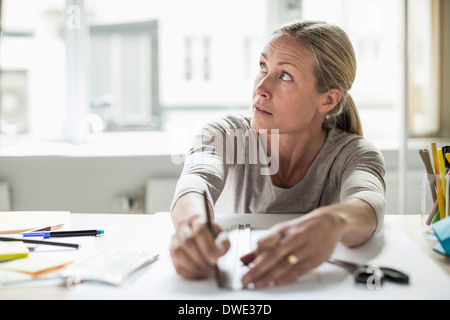 Businesswoman drawing ligne à l'aide de la règle du papier tout en regardant ailleurs Banque D'Images