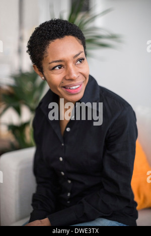 Thoughtful mature woman sitting in living room Banque D'Images