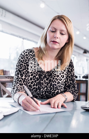 Businesswoman signature document à table de restaurant Banque D'Images