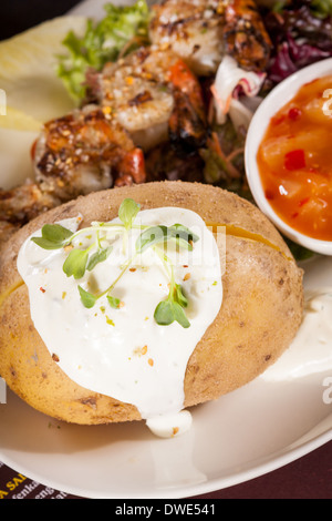 Gambas grillées avec une laitue à feuilles vertes et salade d'endives et de pommes de terre surmontée d'une veste avec de la crème servi sur une plaque blanche, Close up high angle view on white Banque D'Images