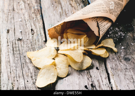 Cornet de papier avec les chips de pomme de terre avec du sel et poivre sur les tables en bois. Voir la série Banque D'Images