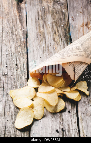 Cornet de papier avec les chips de pomme de terre avec du sel et poivre sur les tables en bois. Voir la série Banque D'Images
