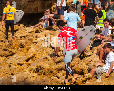 Kelly Slater au large de surfer dans la compétition du Championnat du Monde de Bells Beach avec d'autres surfers et les spectateurs sur les rochers Banque D'Images