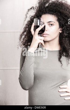 Une jeune femme brésilienne avec un verre de vin rouge. Banque D'Images