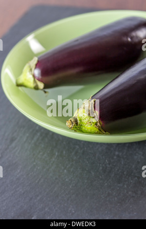 Deux Aubergines dans un bol en verre sur une plaque de schiste noir Banque D'Images