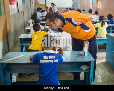 Mae Sot, Tak, en Thaïlande. 6Th Mar, 2014. L'enseignant travaille avec les élèves de l'école bleu ciel. Il y a environ 140 élèves de l'école bleu ciel, au nord de Mae Sot. L'école est à côté de la décharge principale de Mae Sot et sert les enfants des personnes qui travaillent dans la décharge. L'école s'appuie sur les subventions et les dons d'Organisations Non Gouvernementales (ONG). Les réformes dans le Myanmar ont alllowed les ONG pour l'exploitation de l'homme au Myanmar, à la suite de nombreuses ONG sont le déplacement des ressources aux opérations au Myanmar, laissant les migrants et les réfugiés birmans en Thaïlande vulnérables. Le ciel bleu l'école n'est pas ab Banque D'Images