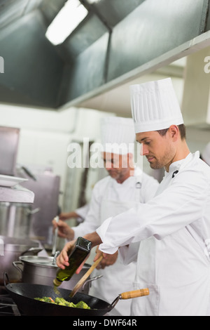 La friture Chef le brocoli dans un wok et ajouter de l'huile d'olive Banque D'Images