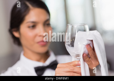 Jolie serveuse polissage d'un verre de vin Banque D'Images