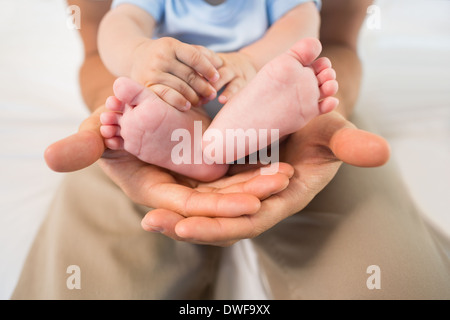 Père holding baby son en bleu babygro Banque D'Images