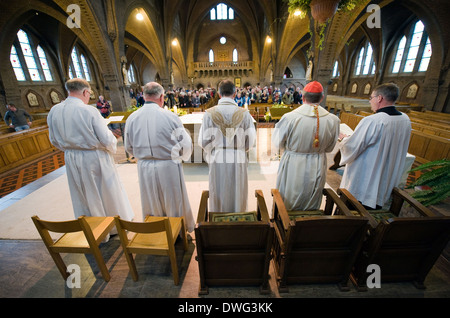 Un prêtre, un cardinal (bouchon rouge) et leurs assistants sont debout pendant une messe dans l'église catholique "Onze Lieve Vrouwekerk' Banque D'Images