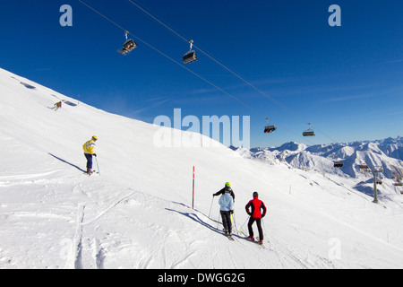 Four skiers preparing to ski down sunny ski slope. Banque D'Images