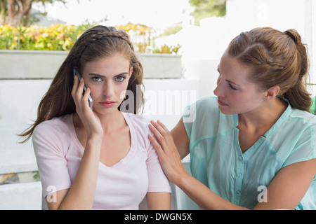 Femme à un ami lorsque consolant shes sur├⌐ fac en appel Banque D'Images