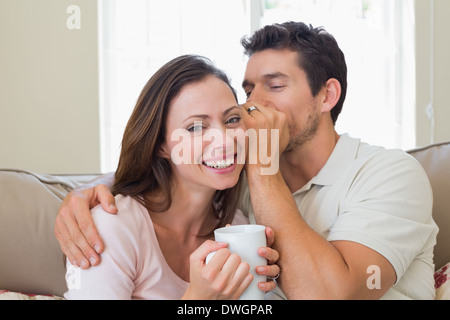 L'homme secret whispering dans une oreille de femme dans la salle de séjour Banque D'Images